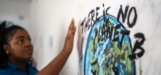 Student fixing a poster on the wall about environmental issues - There is no planet B