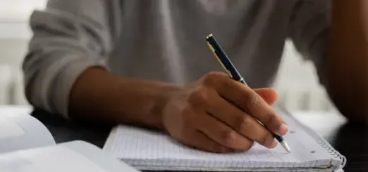 A man holds a pen over a notebook