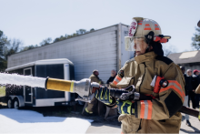 A firefighter sprays firefighting foam from a hose