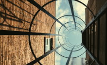 A photo looking up between brick buildings through a glass cylinder