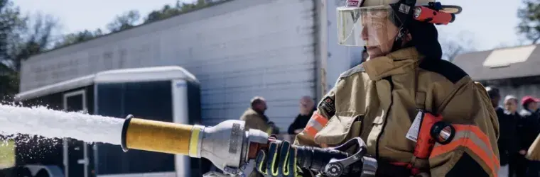 A firefighter sprays firefighting foam from a hose