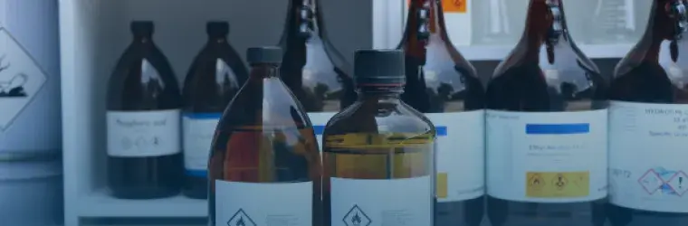 Image shows chemicals in brown bottles in a lab like setting.