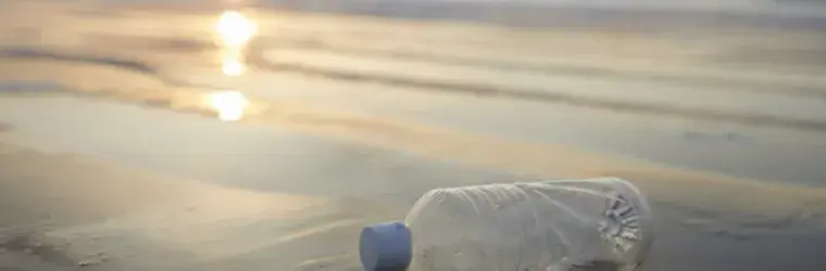 Picture by Canva, plastic bottle by the sea  